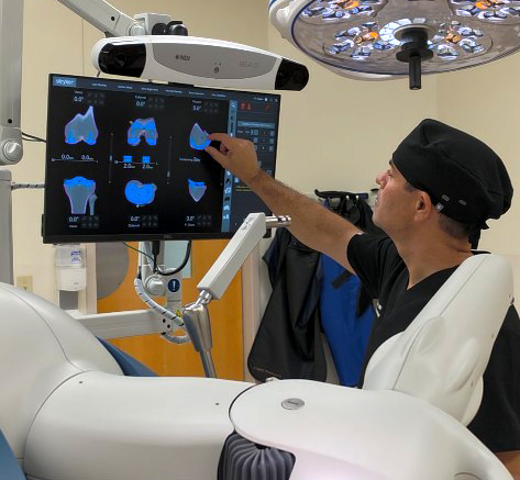 Dr. Michael Higgins looking at a knee bone mapping on a computer screen with the Mako Robot.