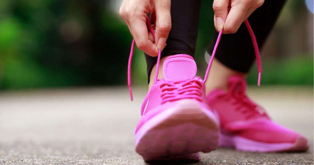 Person lacing up pink tennis shoes top foot pain tidewater orthopaedics