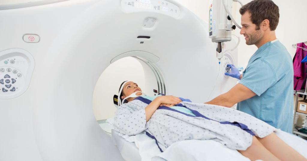 Patient going into a CT imaging machine and is assisted by a CT scan technician